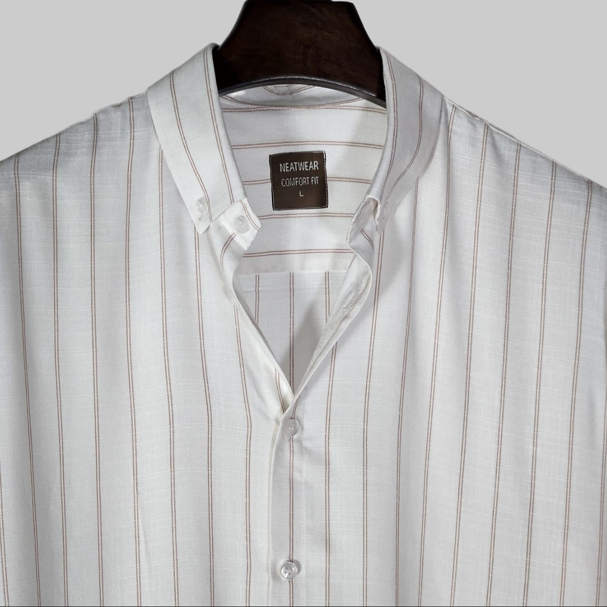 Striped shirt on a hanger with a visible brand label against a light background